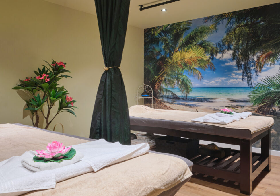 Een kamer met veel planten en twee massagetafels